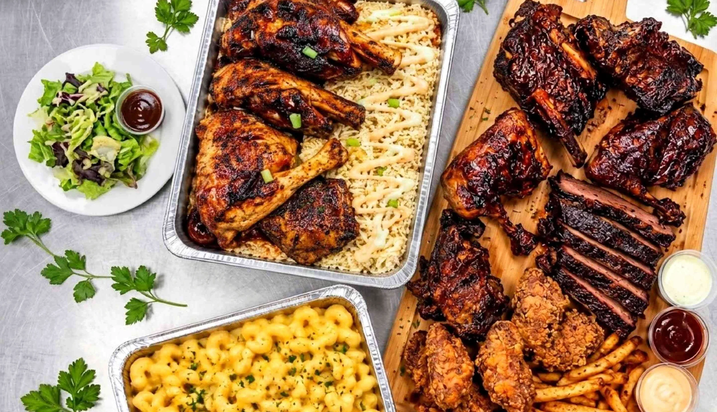 Halal BBQ spread of ribs, sliced brisket, smoked chicken quarters on rice, fried chicken, fries, mac and cheese and salad
