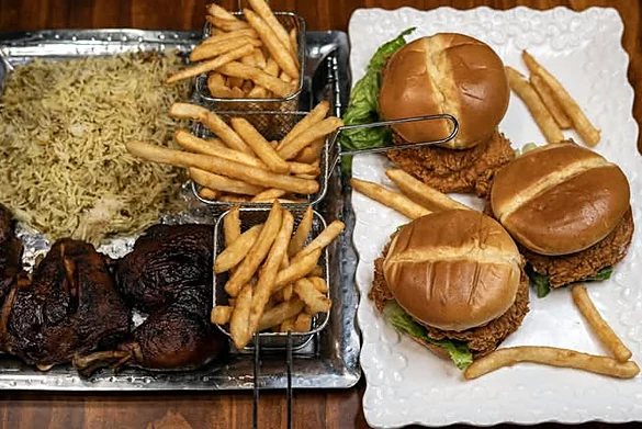 Three crunchy chicken burgers, smoked chicken legs, rice and fries on serving trays